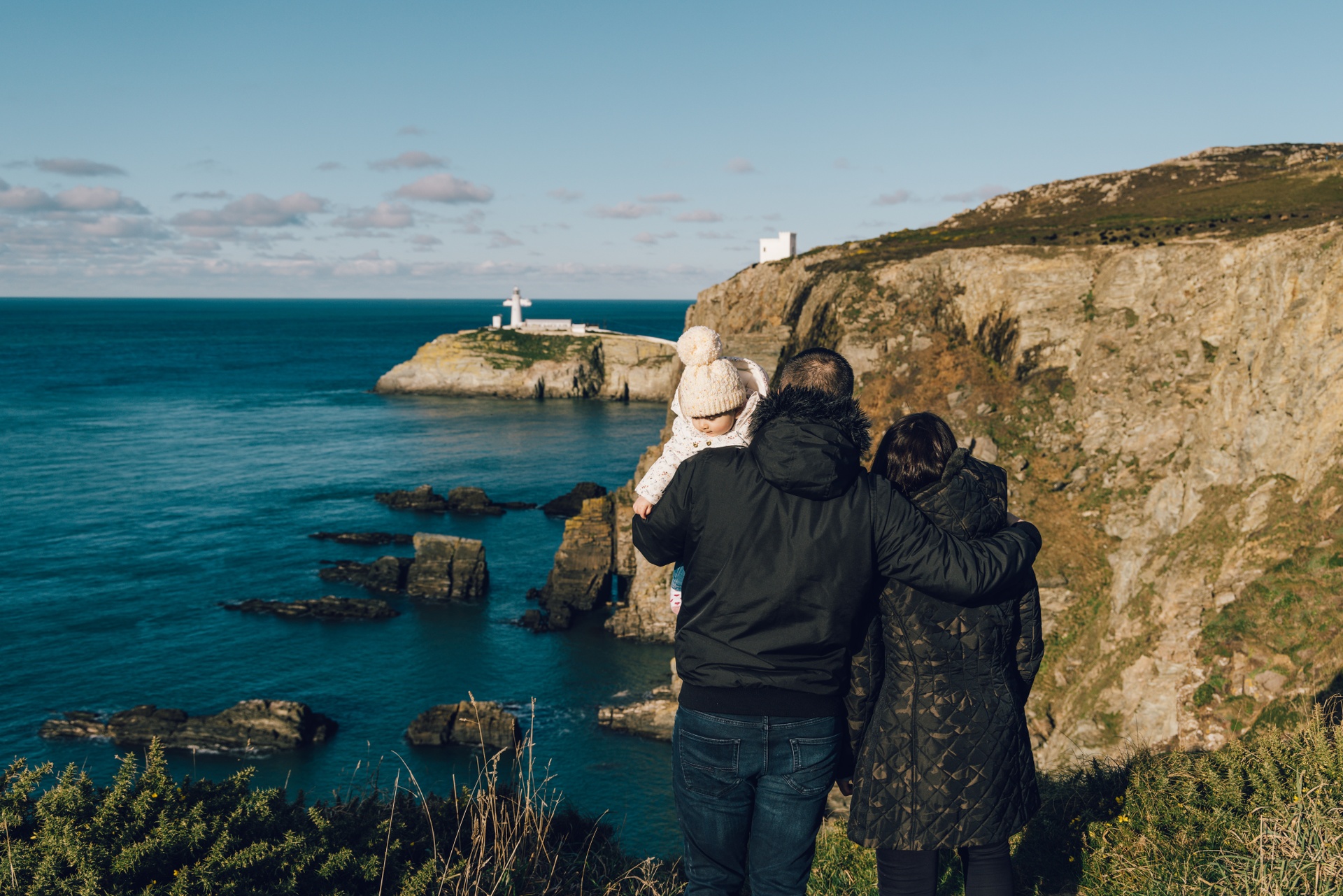 family with baby on coastline